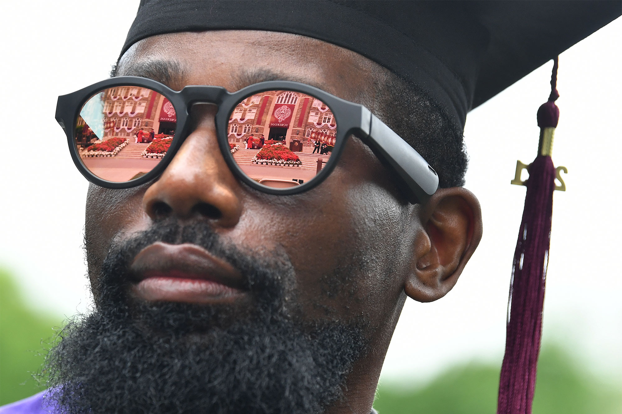 close up of graduates face with reflection of Fordham in his sunglasses