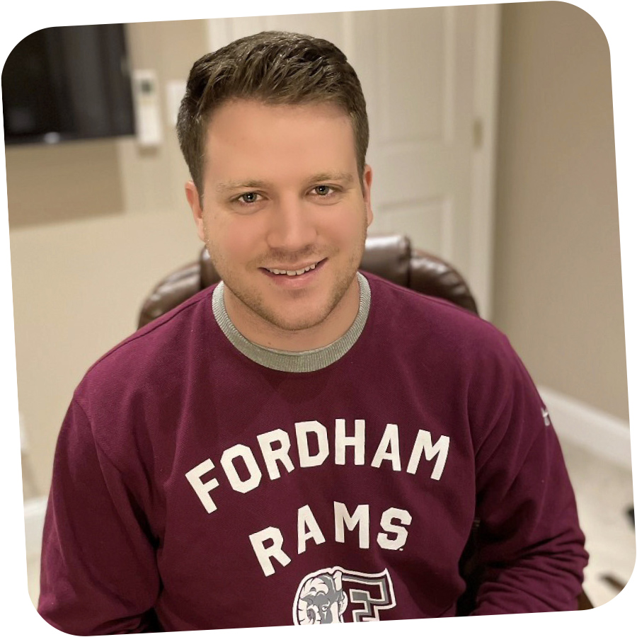 Kevin Burns in Fordham crewneck smiling in office chair