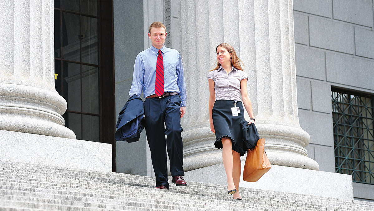 Man and woman in business wear walking down courthouse steps