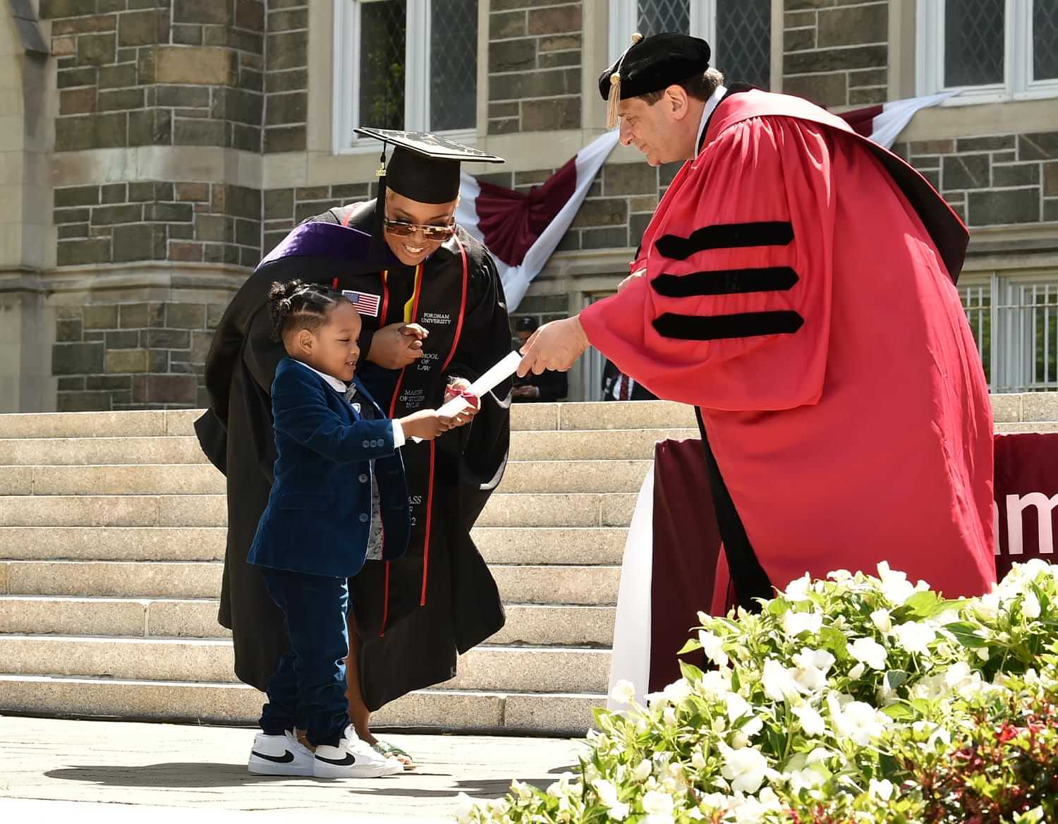the dean hands a small child a ribbon tied diploma on stage