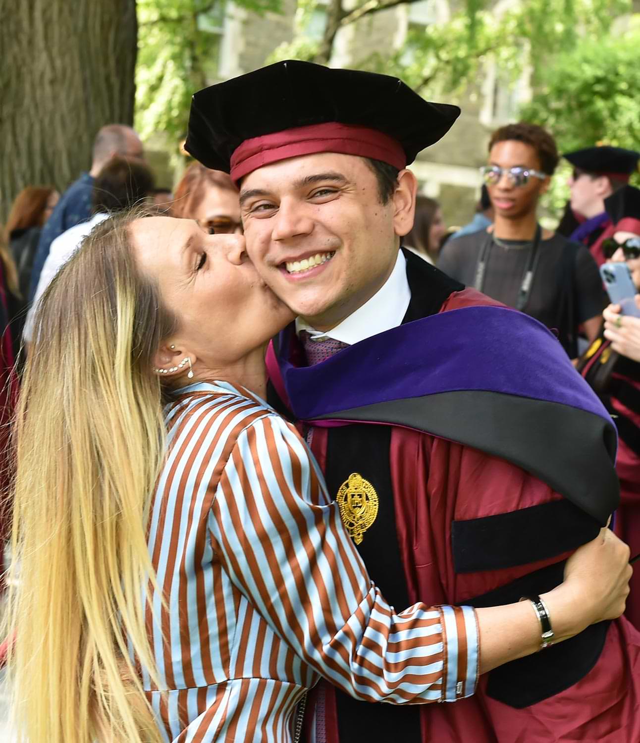 a smiling graduate receiving a big kiss on the cheek