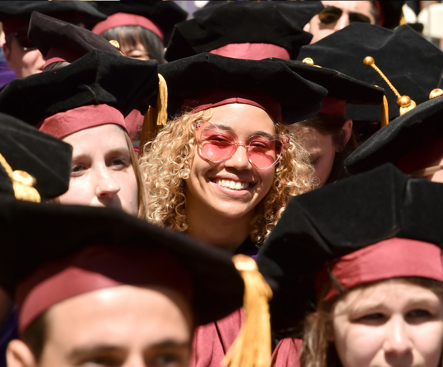 a graduate smiles at the camera while seated during the ceremony