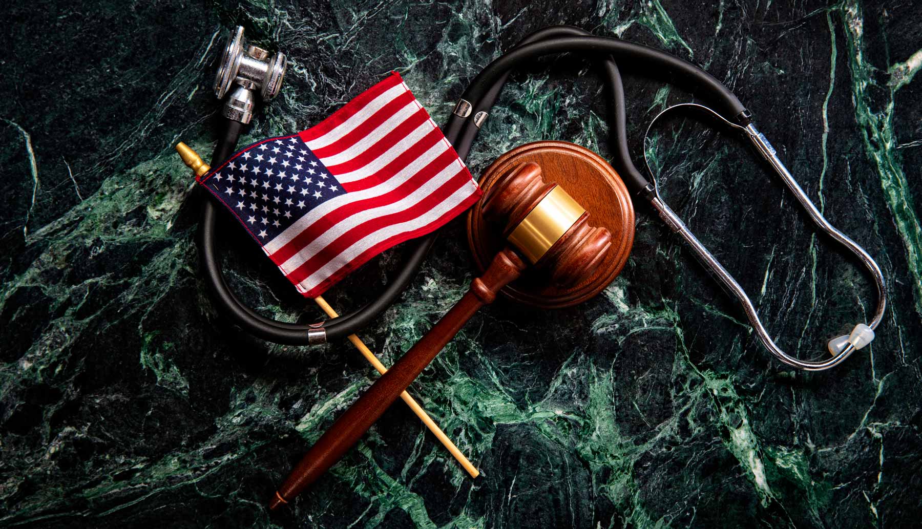flag, gavel, and stethoscope laying on granite