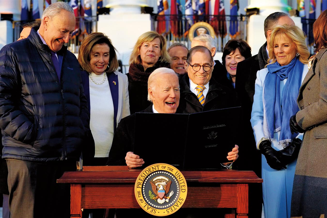 Rep. Nadler stands with a group of others behind President Biden as he holds a bill