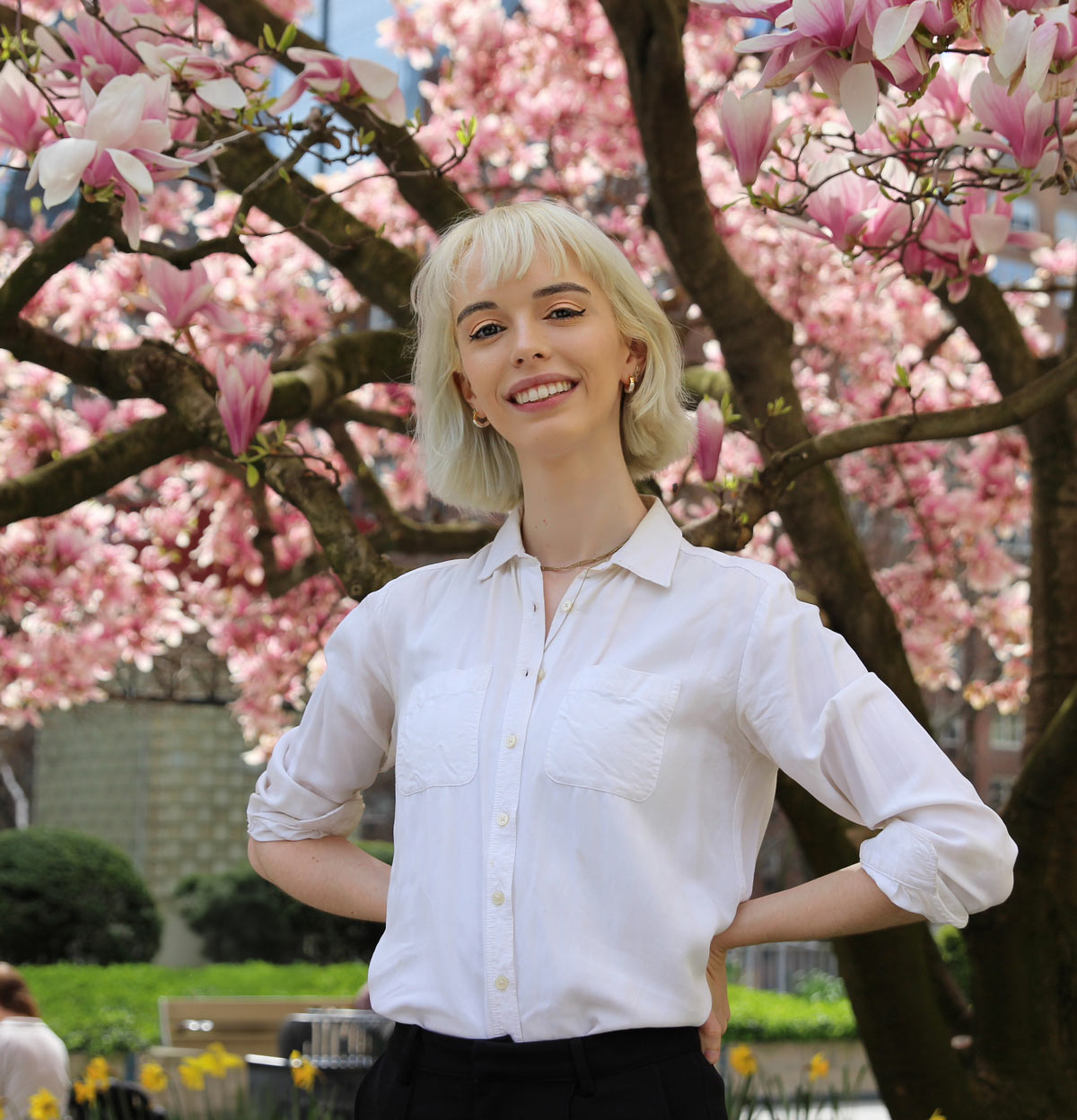 portrait image of Carrie Plover standing in front of a large tree growing pink and white flowers