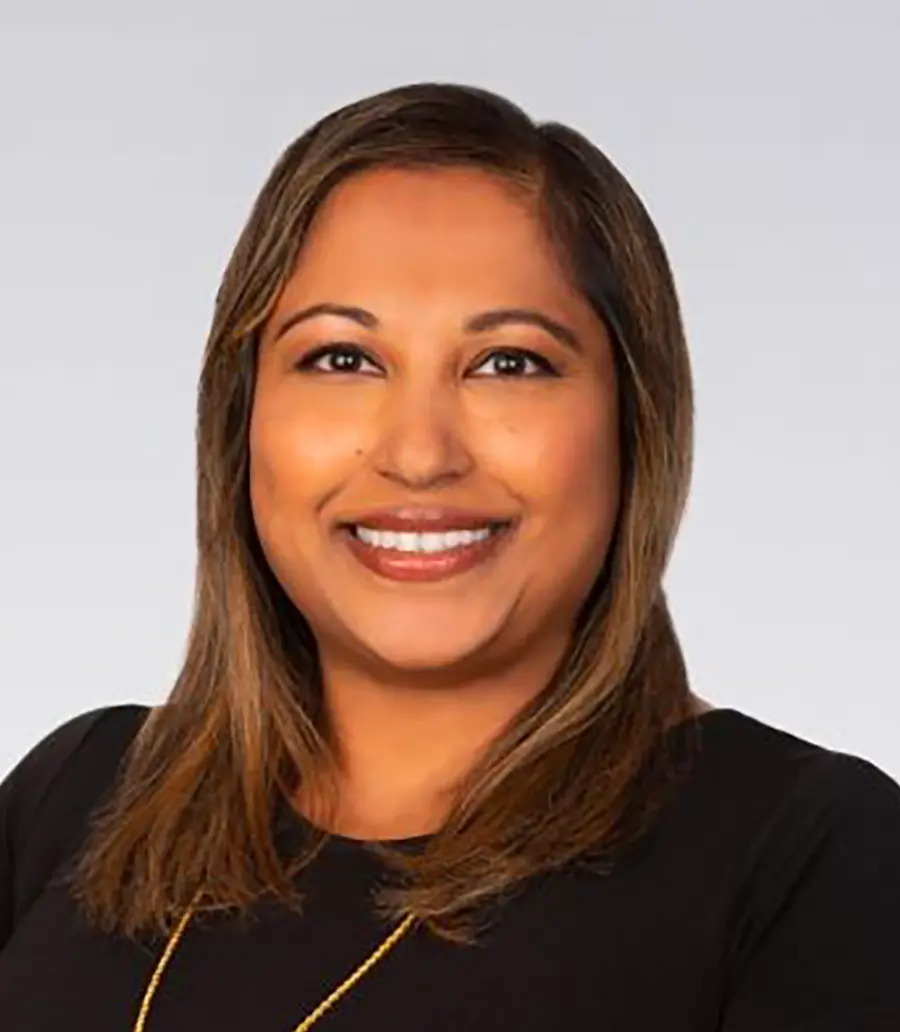 Portrait orientation photograph headshot of Azeema Mohaideen Batchelor, a smiling woman wearing a black top and a gold necklace