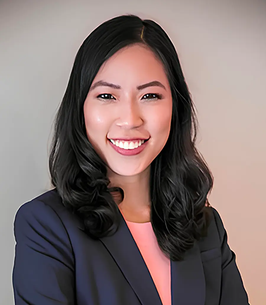 Portrait orientation photograph headshot of Hon. Grace E. Lee, a smiling woman wearing a charcoal black business suit blazer with a pink blouse underneath