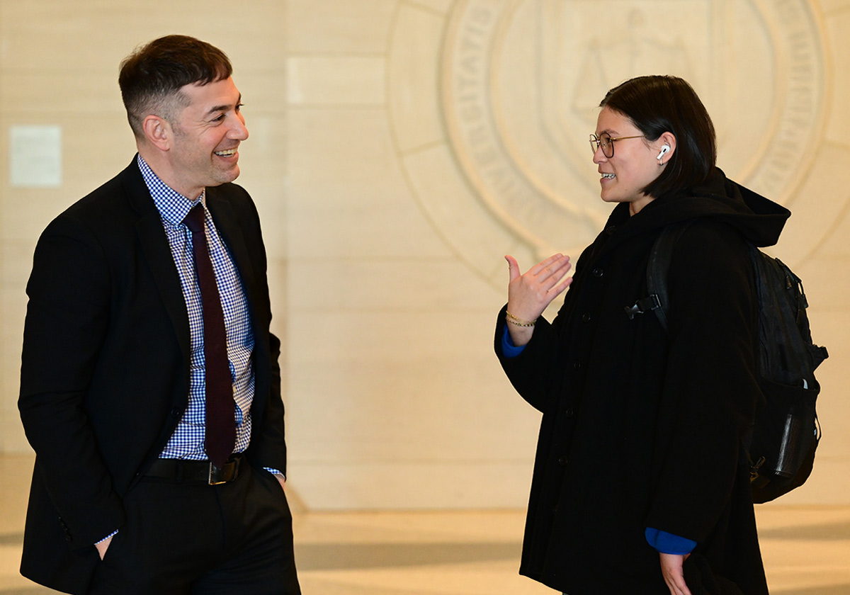 Joseph Landau smiles as he talks with a person wearing glasses and a backpack.