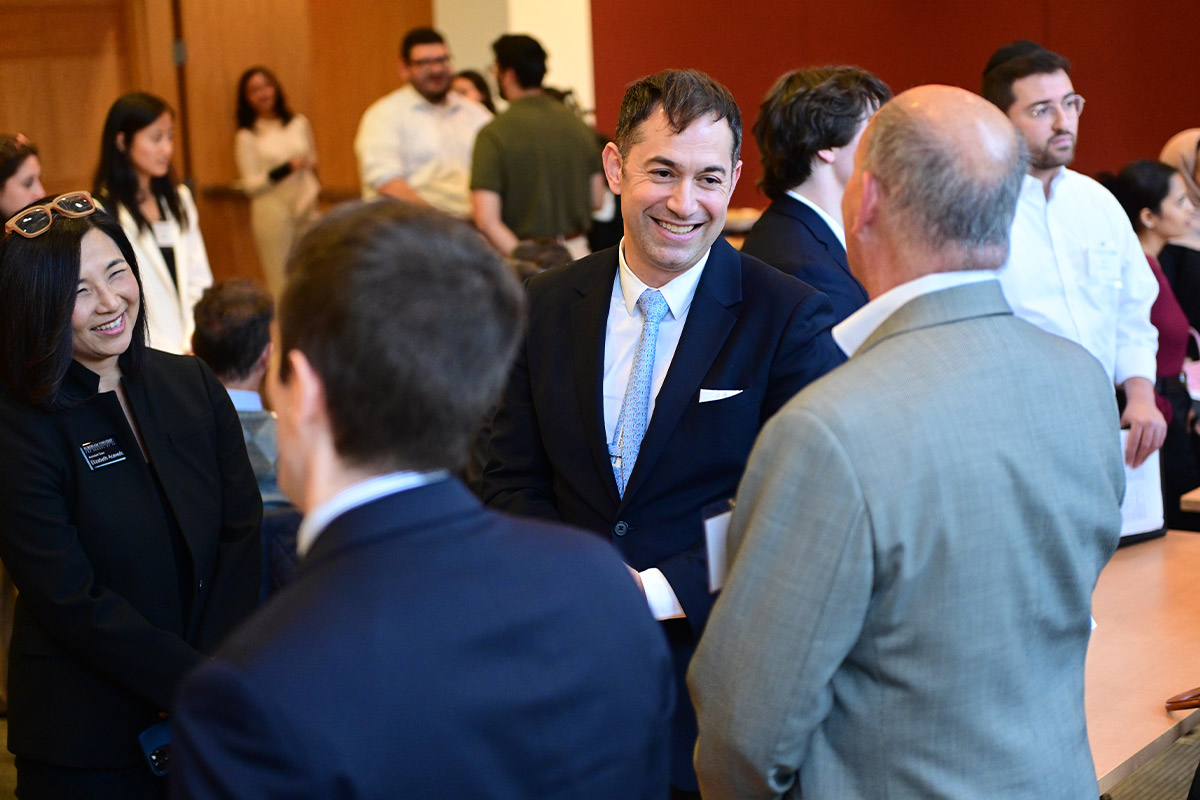 Joseph Landau smiles while talking with people in a crowded room.