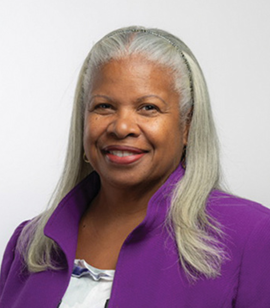 Headshot of Deneen Donnley smiling in a purple business blazer suit