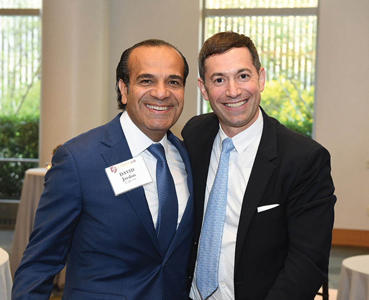 Two smiling men in suits pose together at a Fordham Law event
