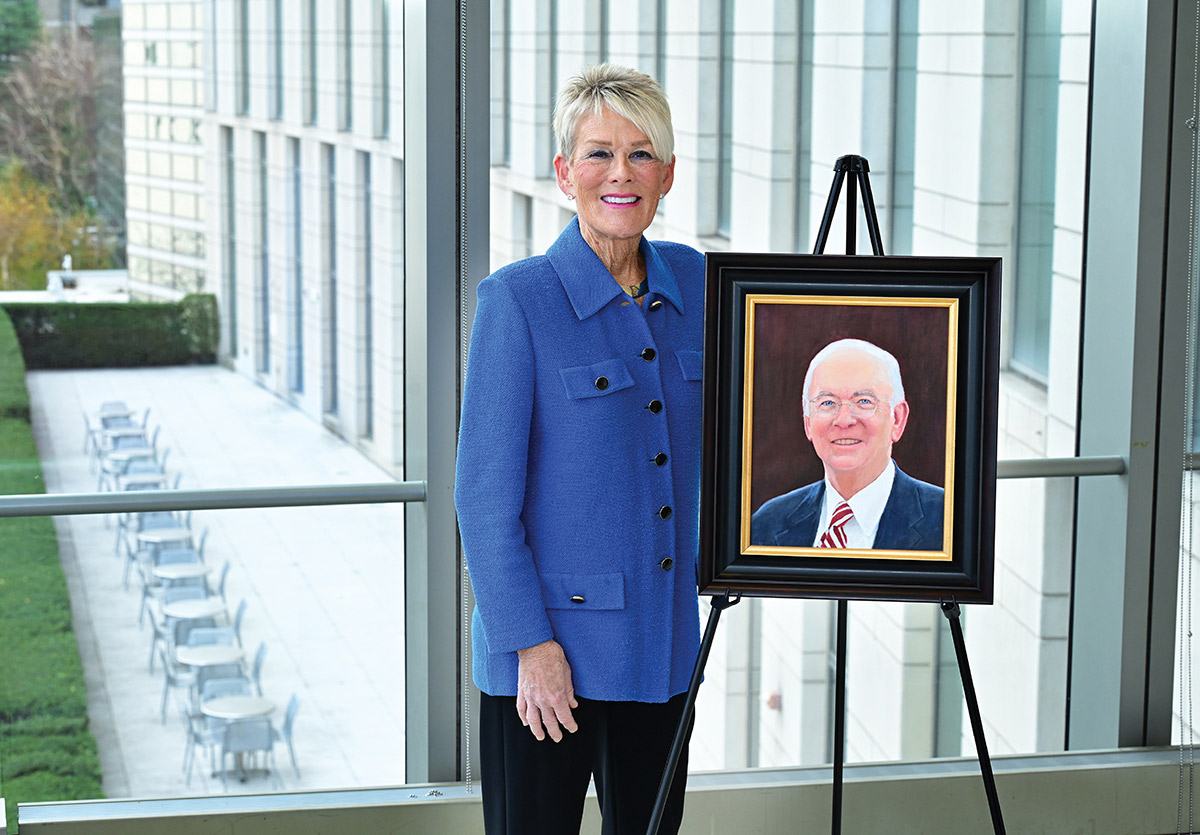 Alice Lehman stands smiling next to a framed portrait of Frank Murphy on an easel.