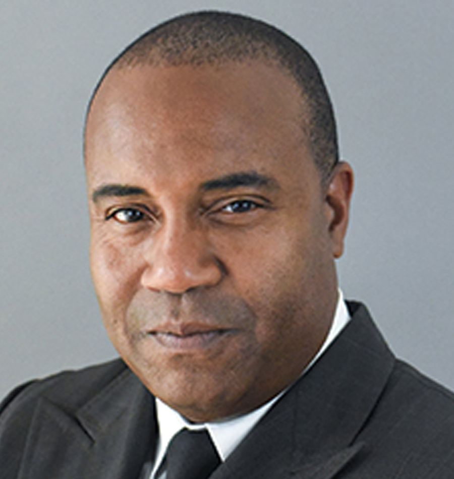 Headshot of Hector Baldonado smiling in a black blazer business suit