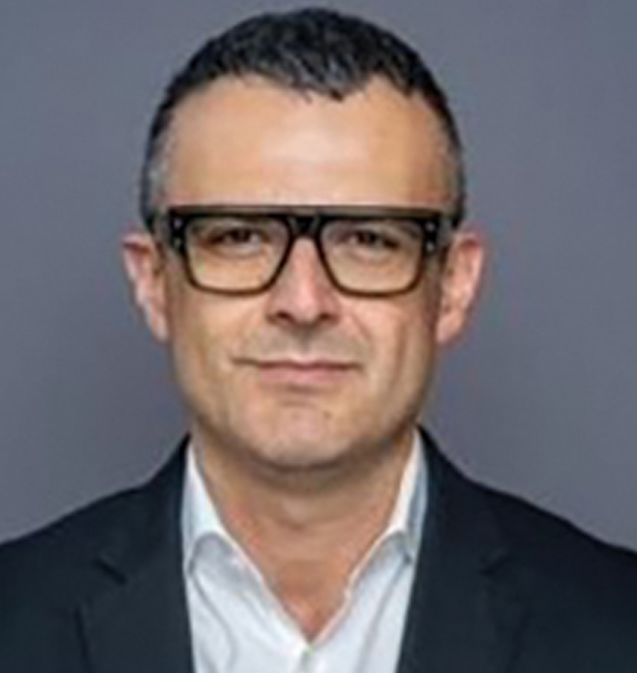 Headshot of Pouya Lavian grinning in a black business blazer suit